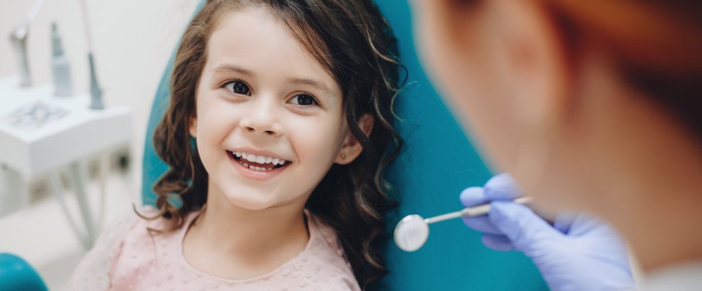A young girl receives pediatric care at the dentist.